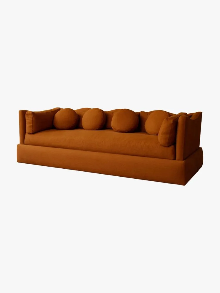 Orange couch with circular pillows and a scalloped back.
